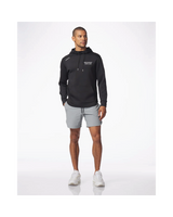 A man modeling a black pullover hoodie with white drawstrings and a small white chest logo, paired with light gray athletic shorts and white sneakers, against a clean white studio background.